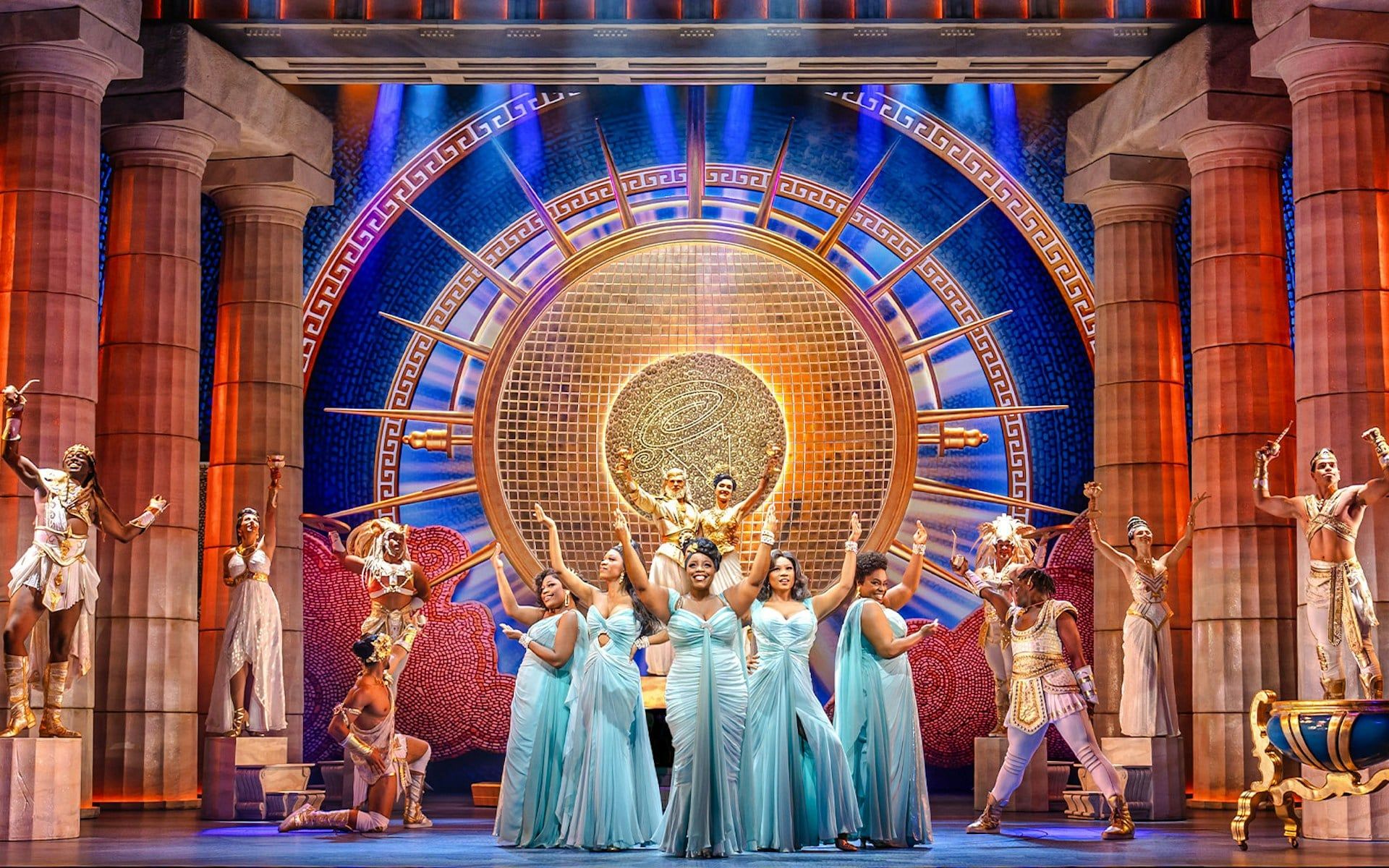 Stage performance of Disney's Hercules with actors in Greek costumes and ornate backdrop
