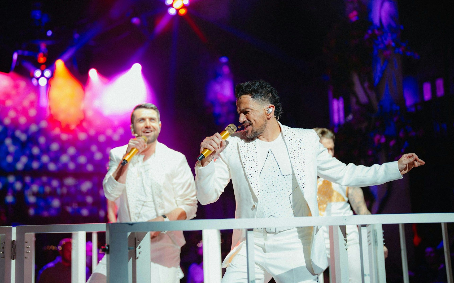 Performers singing at Mamma Mia! The Party with vibrant stage lights
