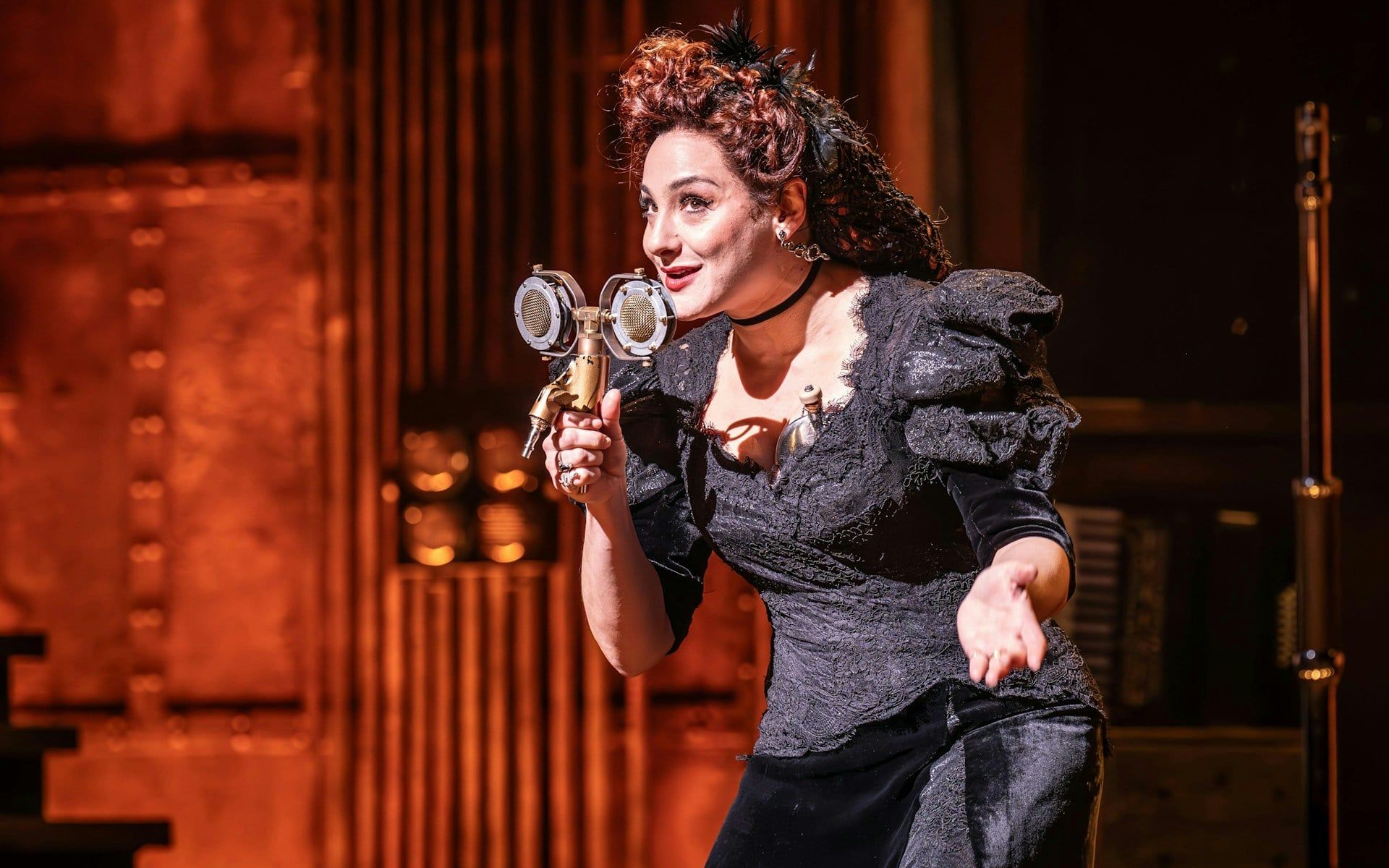 Performer on stage during Hadestown show, West End, holding a vintage microphone
