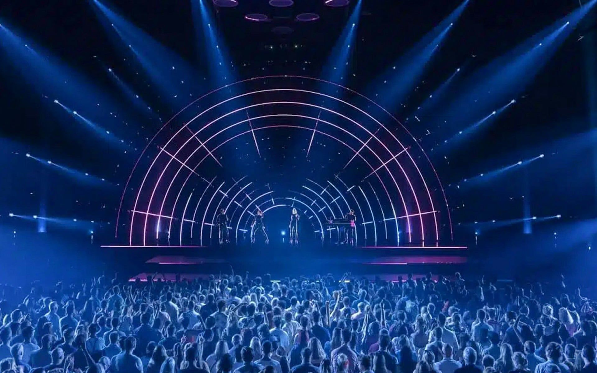 Crowd watching ABBA Voyage concert with illuminated stage and performers
