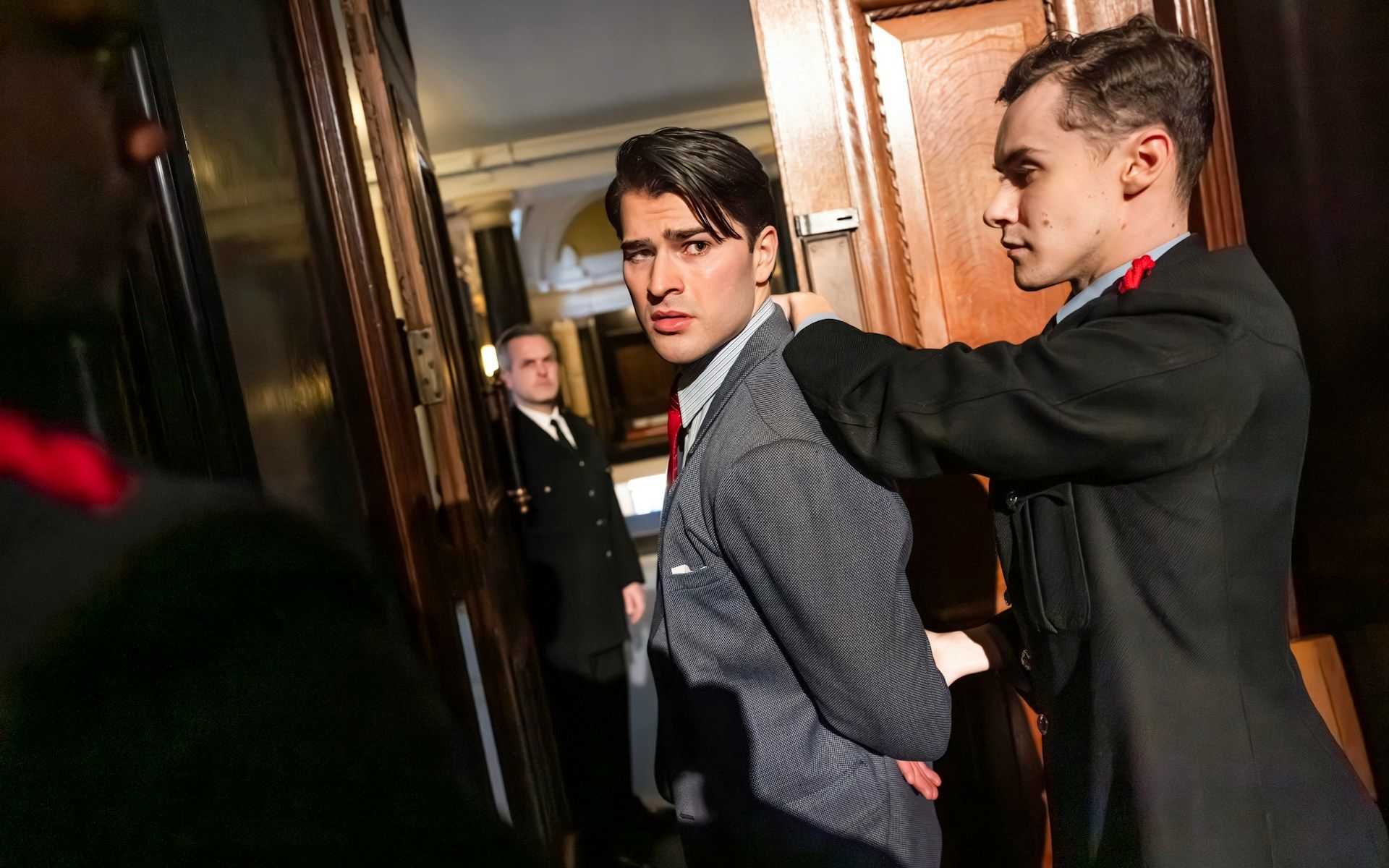 Actor being escorted by guards in a courtroom scene from "Witness for the Prosecution" performance