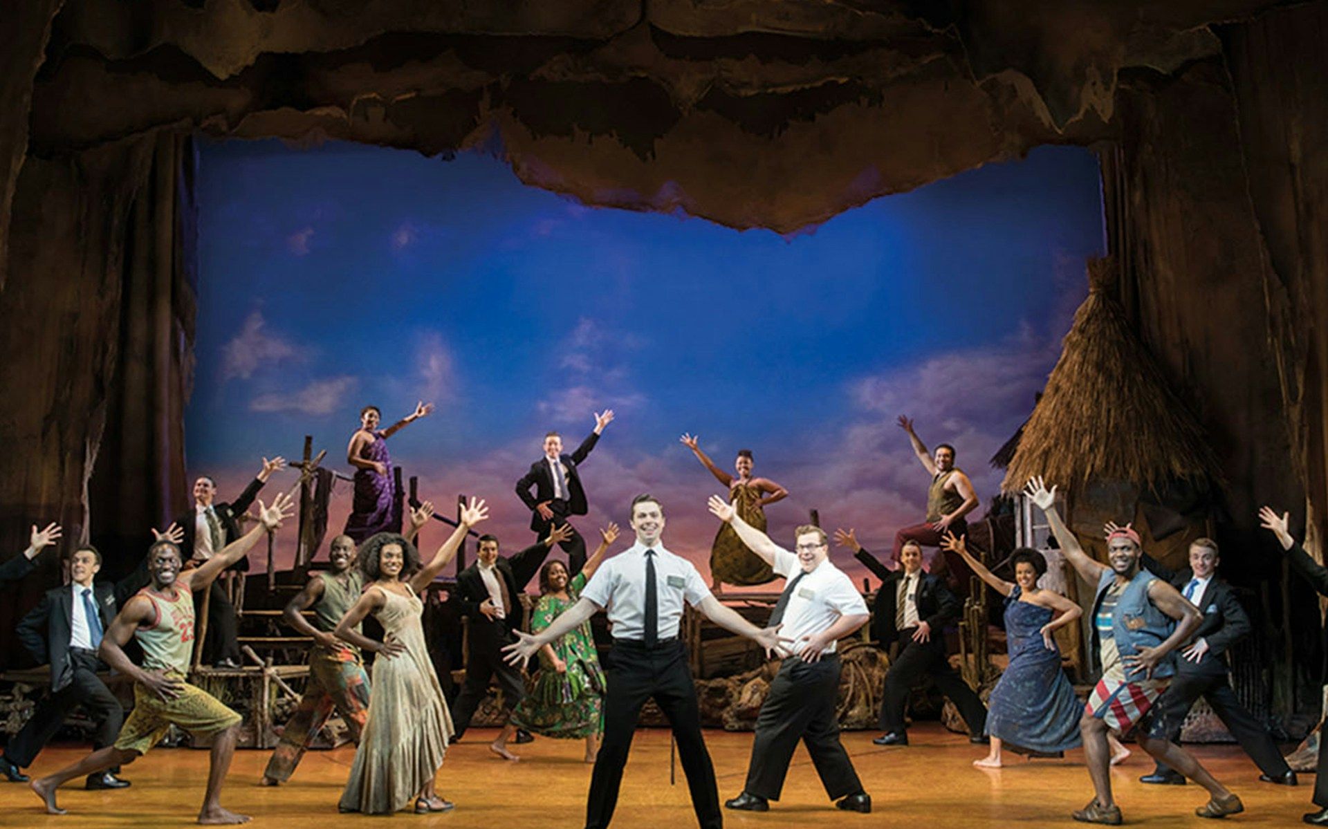Cast performing a scene from The Book of Mormon musical on stage
