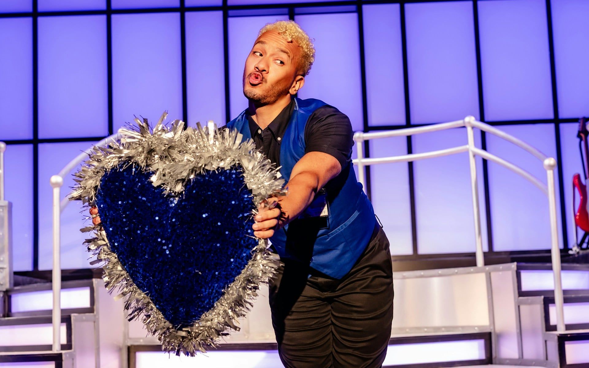 Performer holding a glittery heart prop on stage during Titanique Westend show