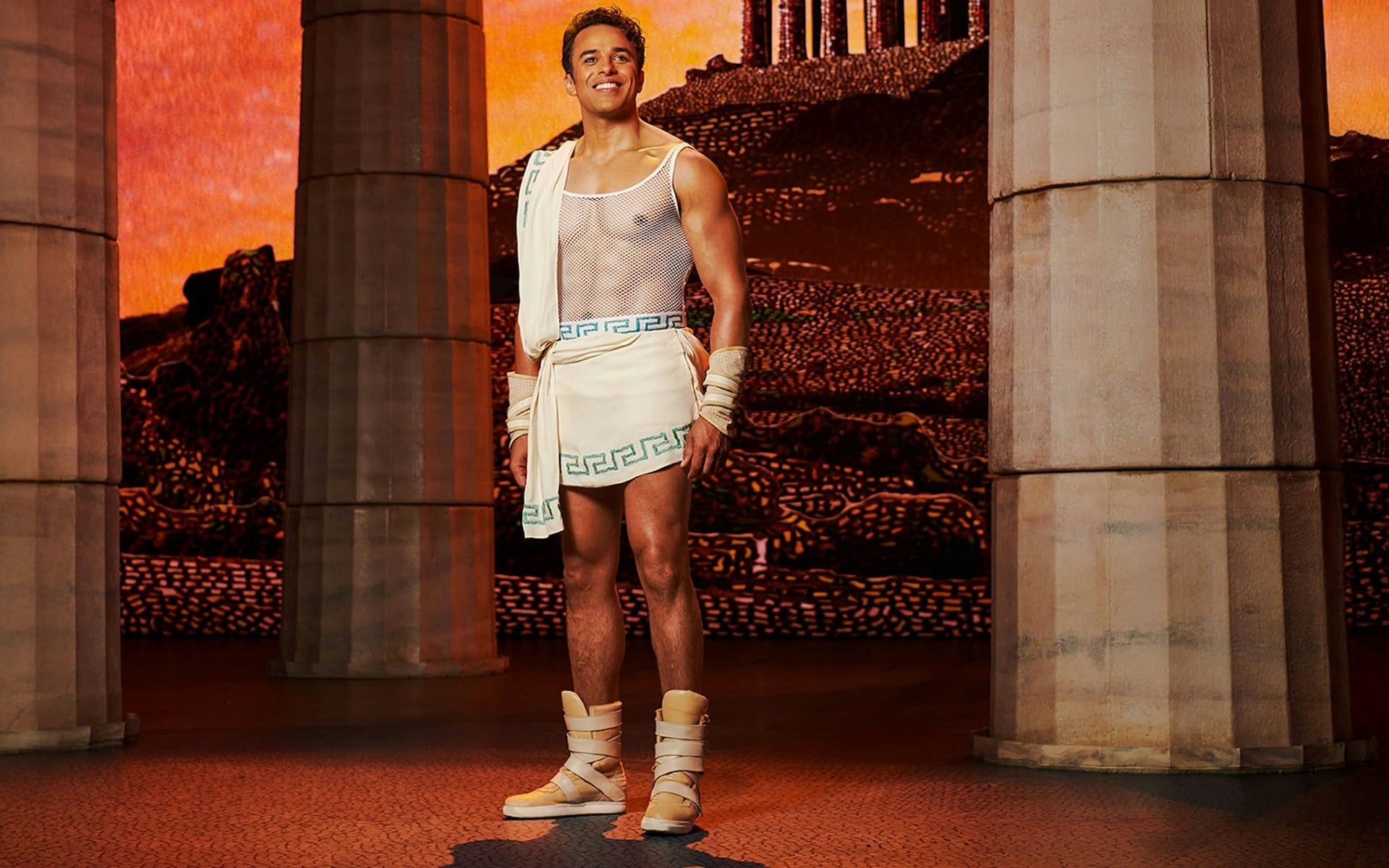 Man in ancient Greek attire stands between columns, representing Disney's Hercules