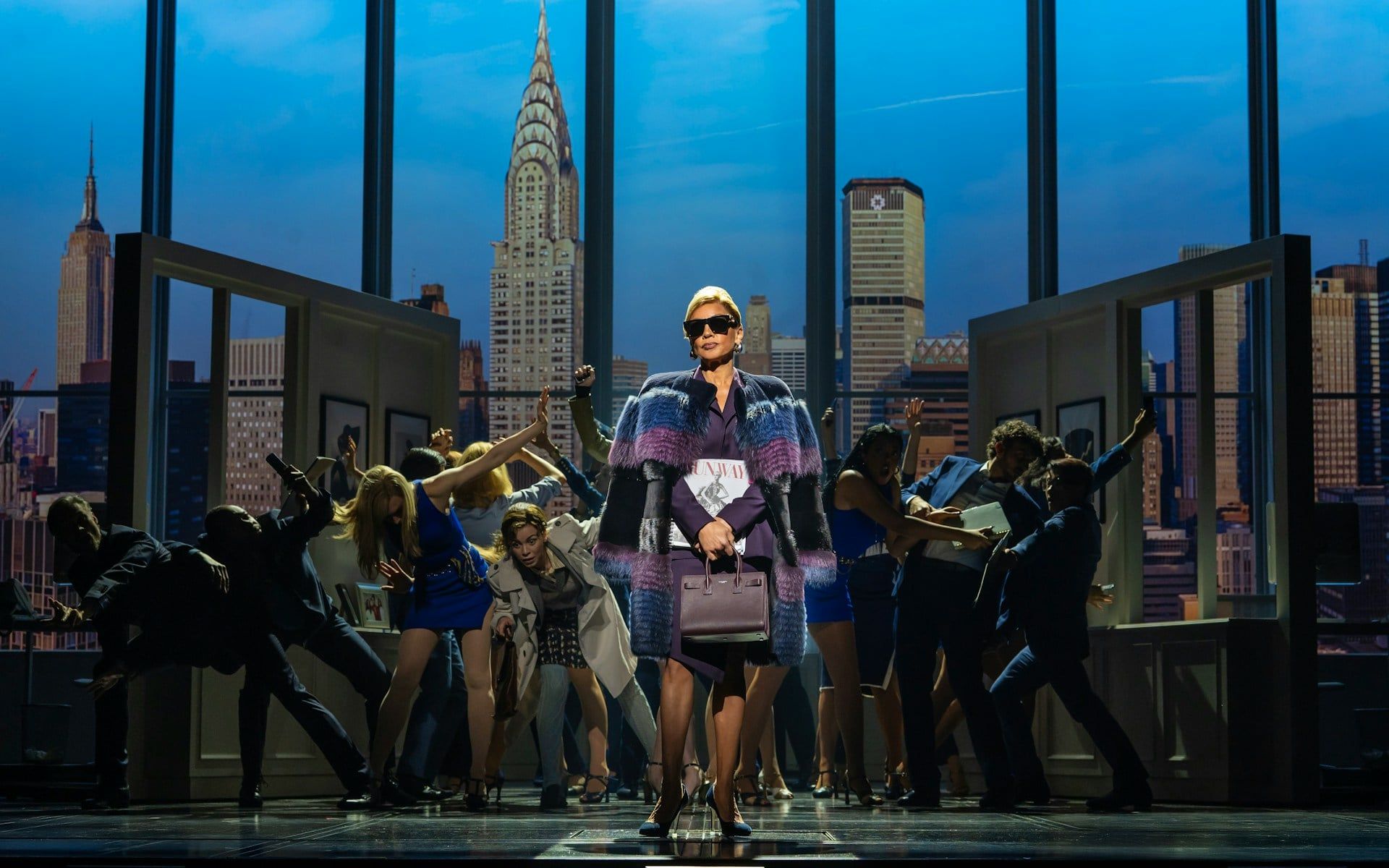 Stage scene from The Devil Wears Prada West End show with city skyline backdrop