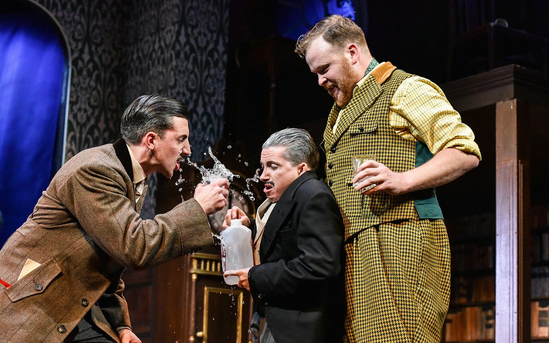 Actors in a comedic scene from "The Play That Goes Wrong" on stage
