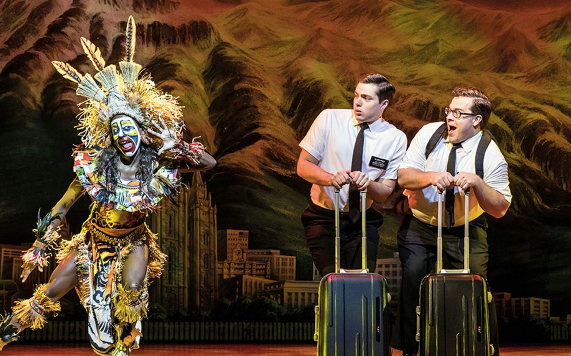 Performers in "The Book of Mormon" musical scene with vibrant costumes and props