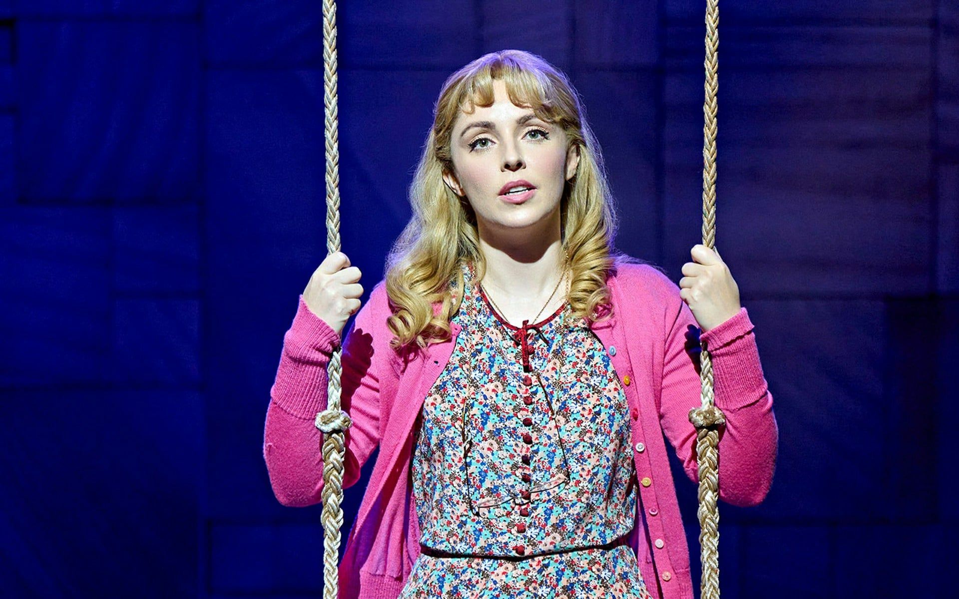 Performer on stage in Matilda The Musical holding a swing rope