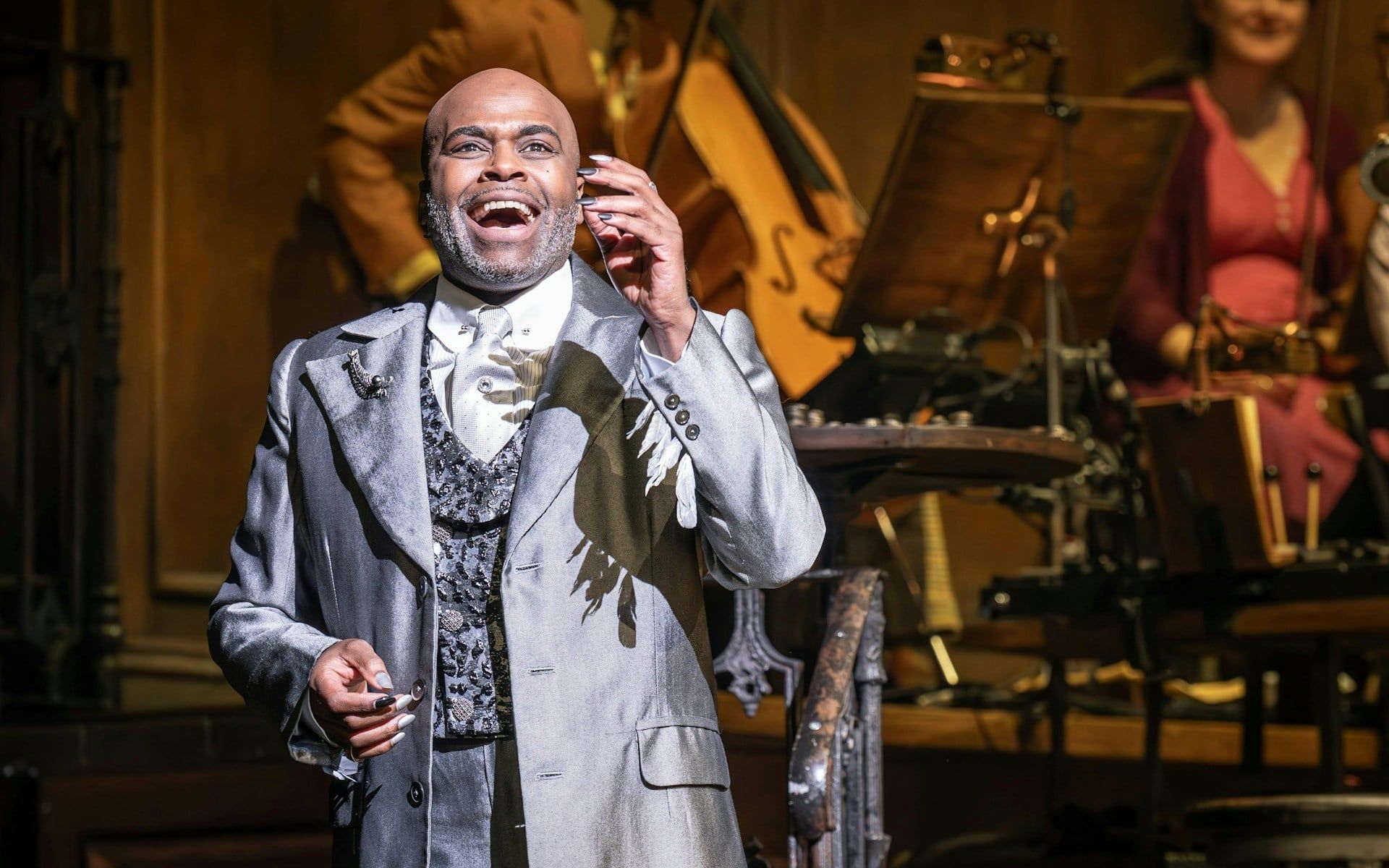 Performer on stage during Hadestown musical, West End, with musicians in the background