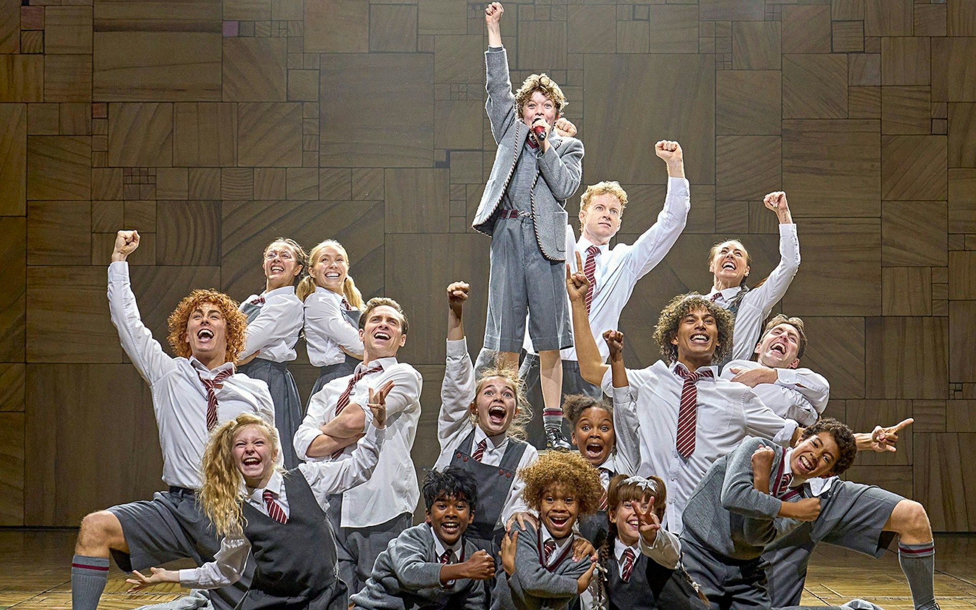 Cast of Matilda The Musical performing on stage with raised fists