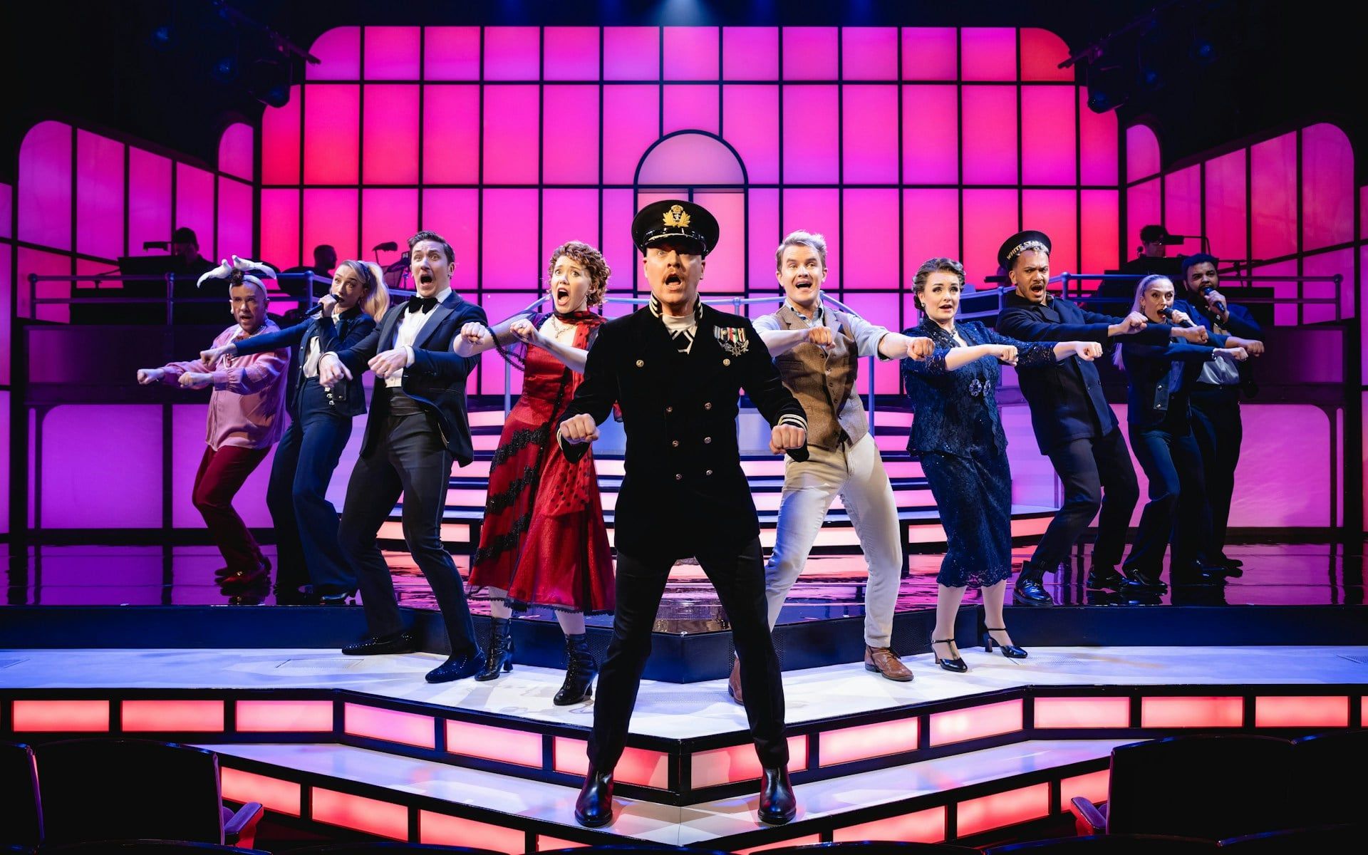 Cast performing a musical number in Titanique Westend with vibrant stage lighting