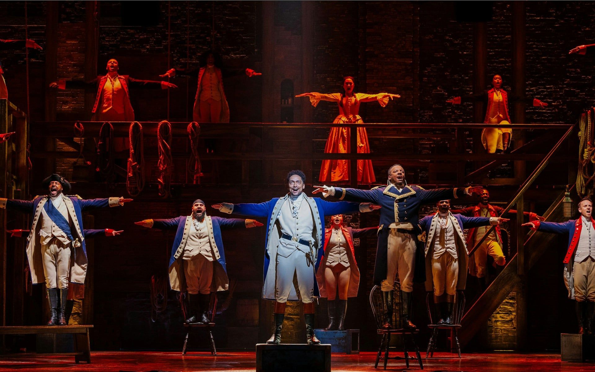 Actors performing a musical number in Hamilton production on stage