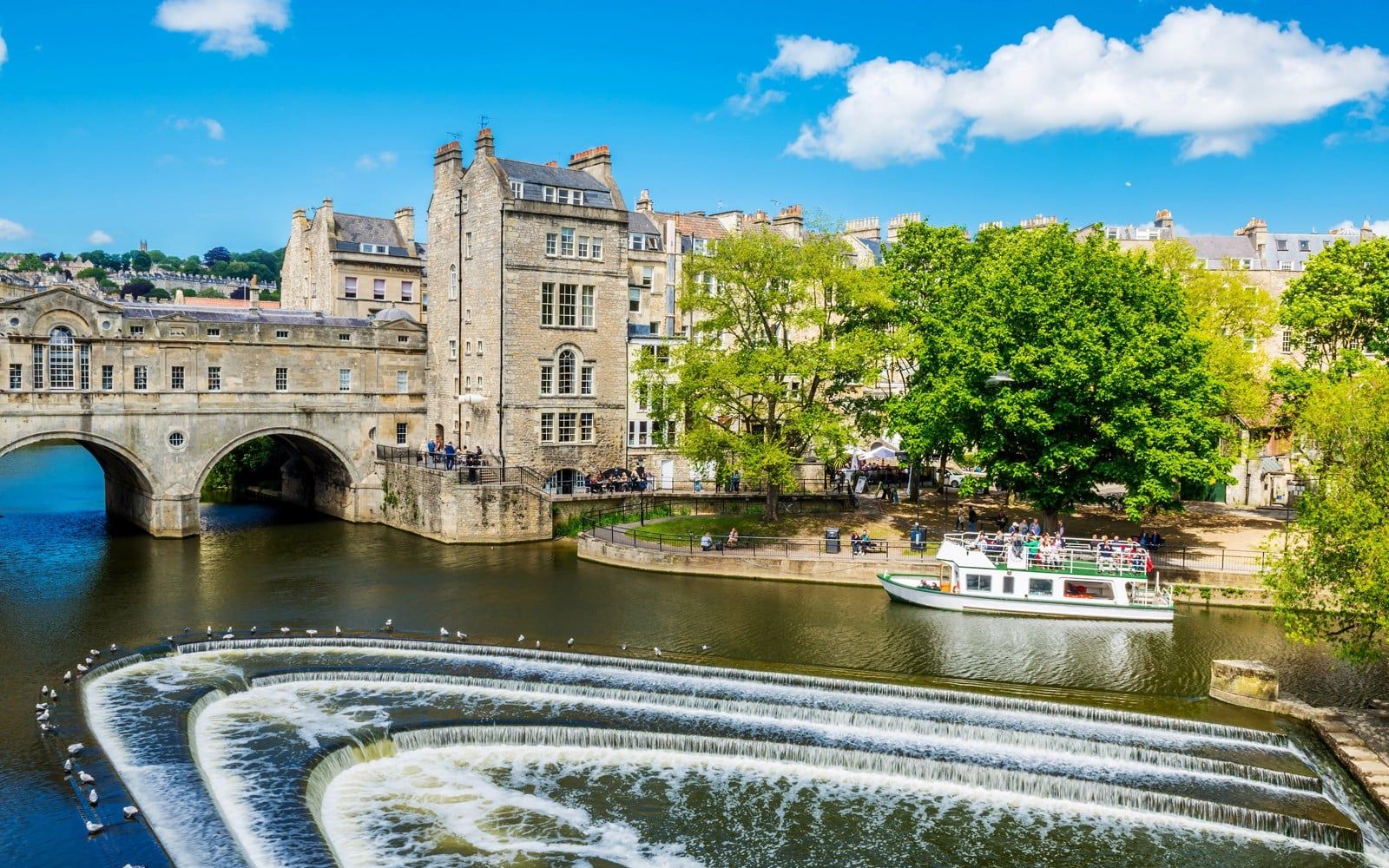 Historic Bath city street with tour group near Pulteney Bridge, live music performance nearby — Bridgerton: 1.5 Hour Guided Tour of Filming Locations in Bath with Music
