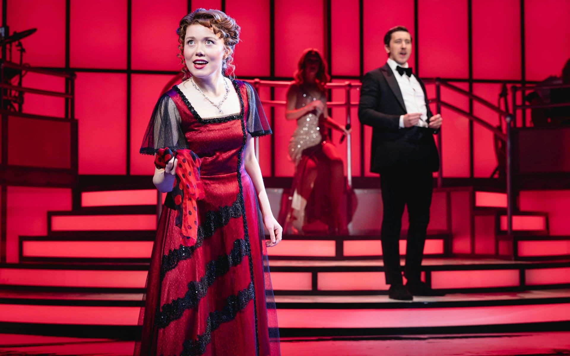 Stage performance of Titanique Westend with actors in period costumes on a red-lit set