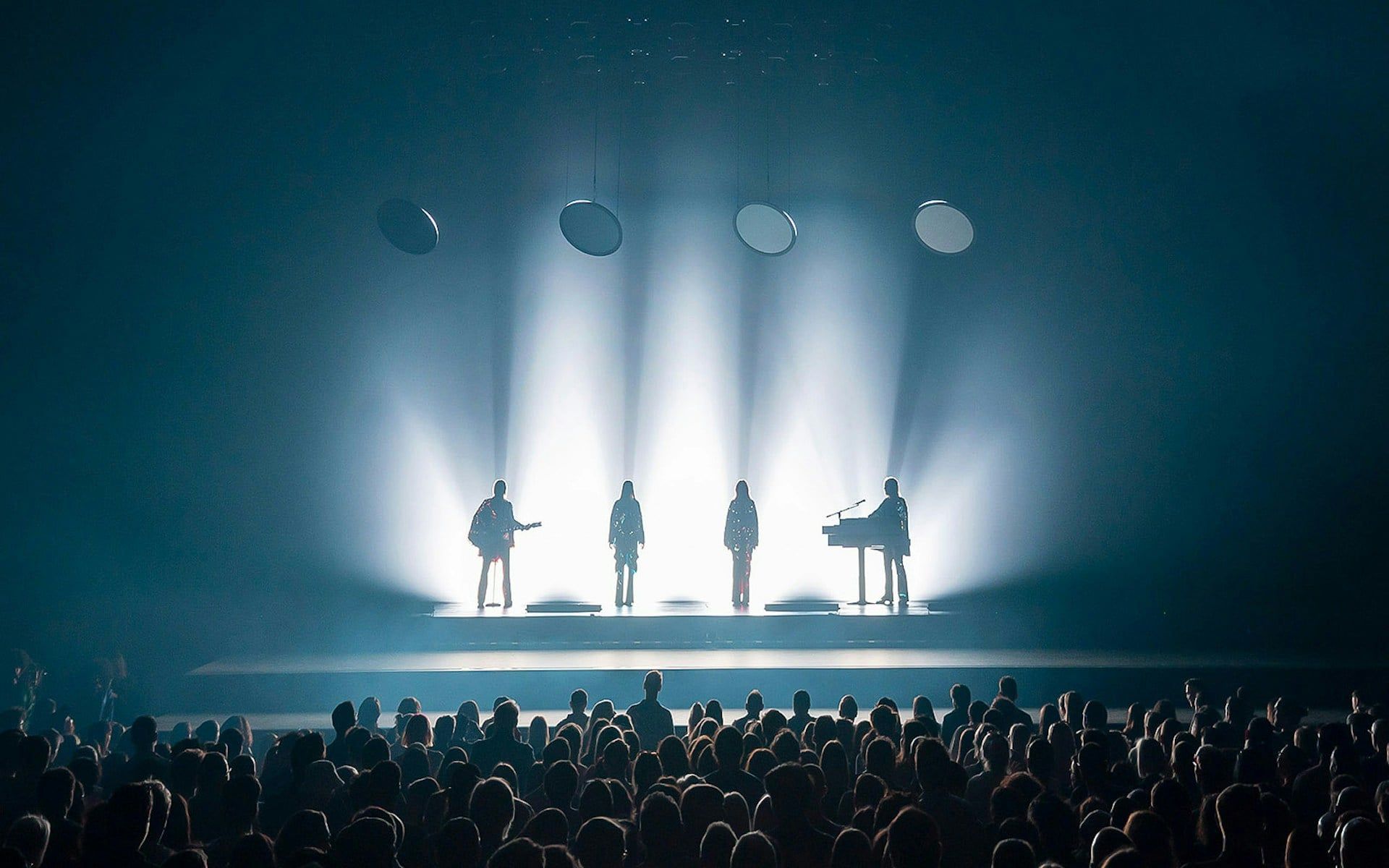 Silhouetted performers on stage with audience at ABBA Voyage show in London