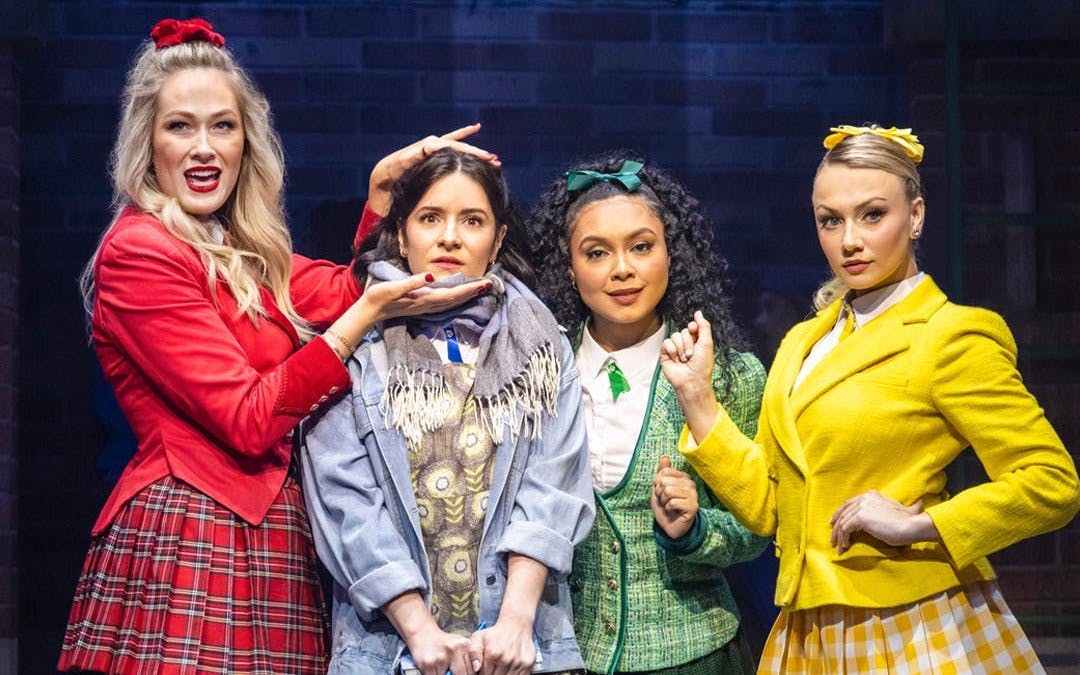 Cast members of Heathers the Musical on West End stage in colorful costumes