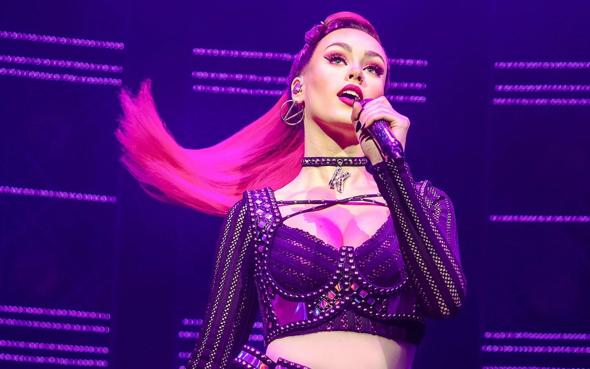 Performer singing on stage during the musical "Six" with vibrant lighting