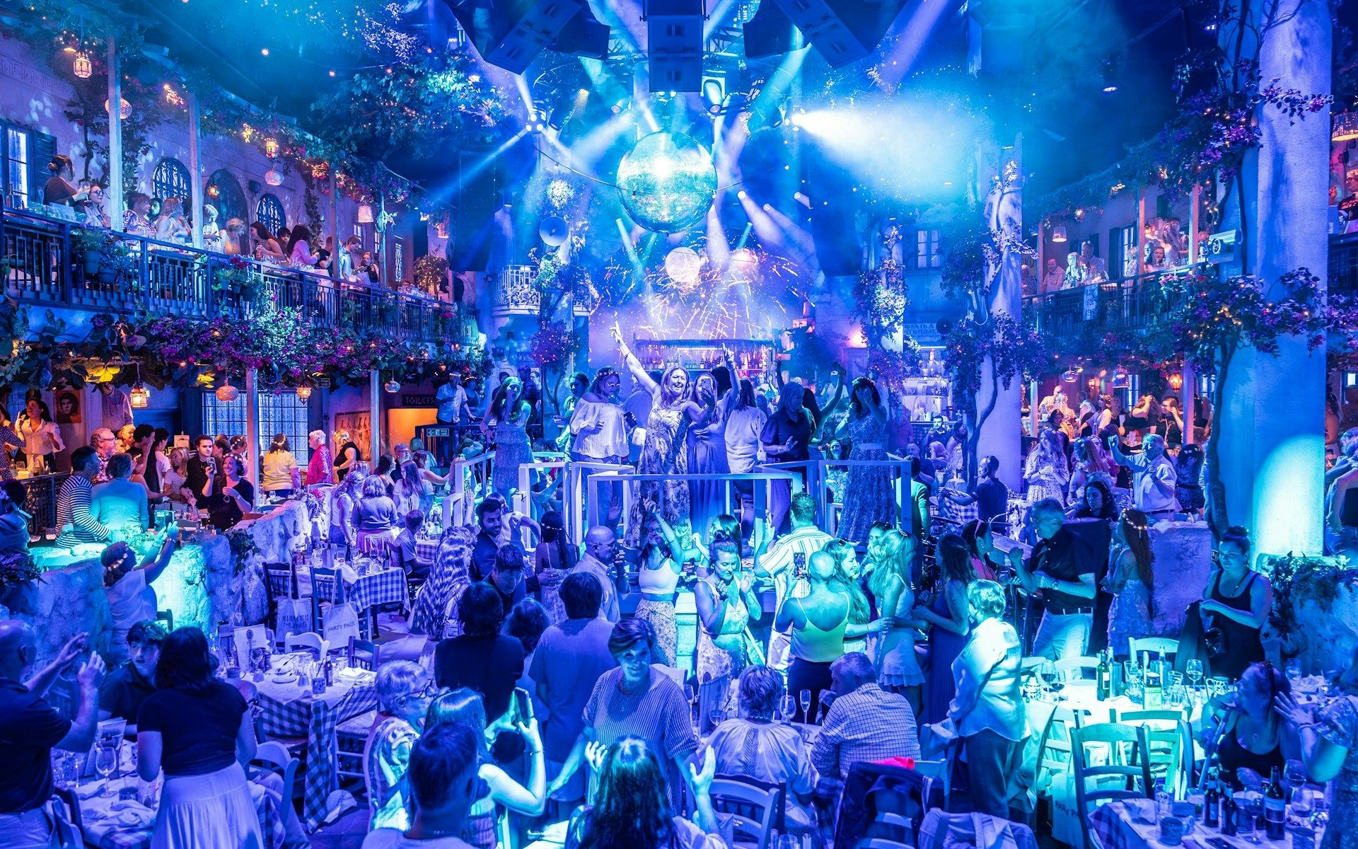 Guests enjoying Mamma Mia! The Party performance with vibrant lights and festive atmosphere