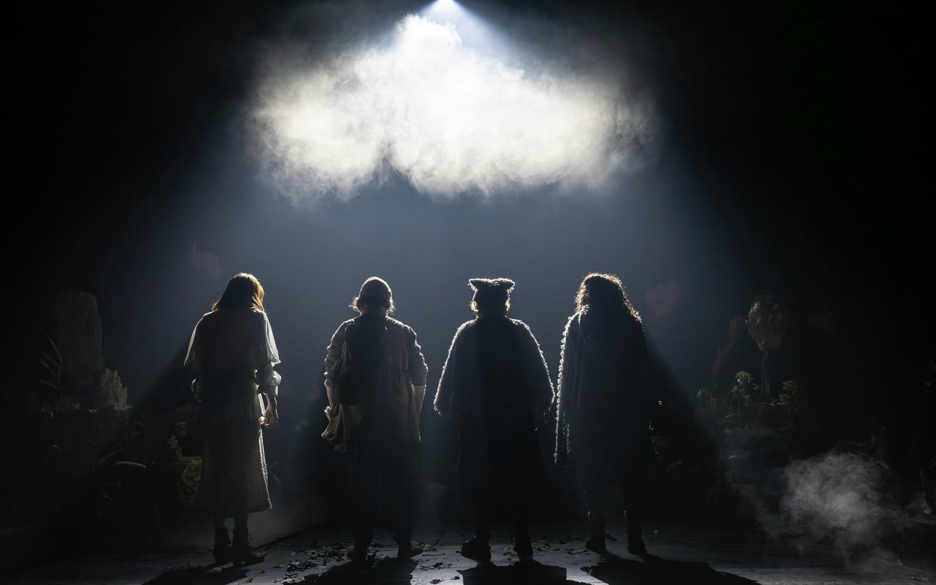 Four actors in costume stand on a dimly lit stage for Into The Woods production