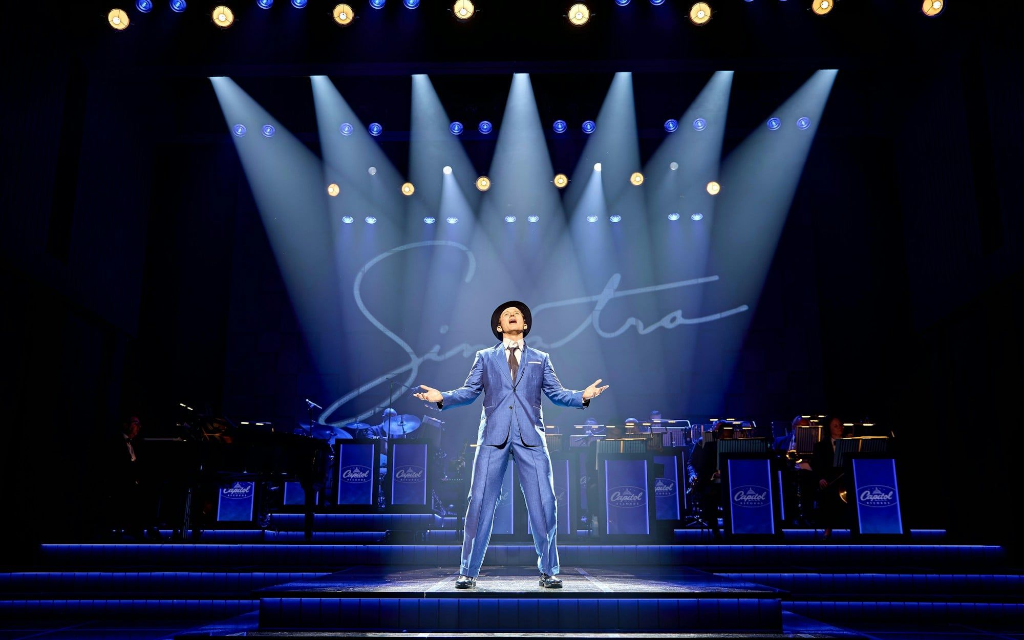 Performer on stage during Sinatra The Musical, Westend, with band and signature backdrop