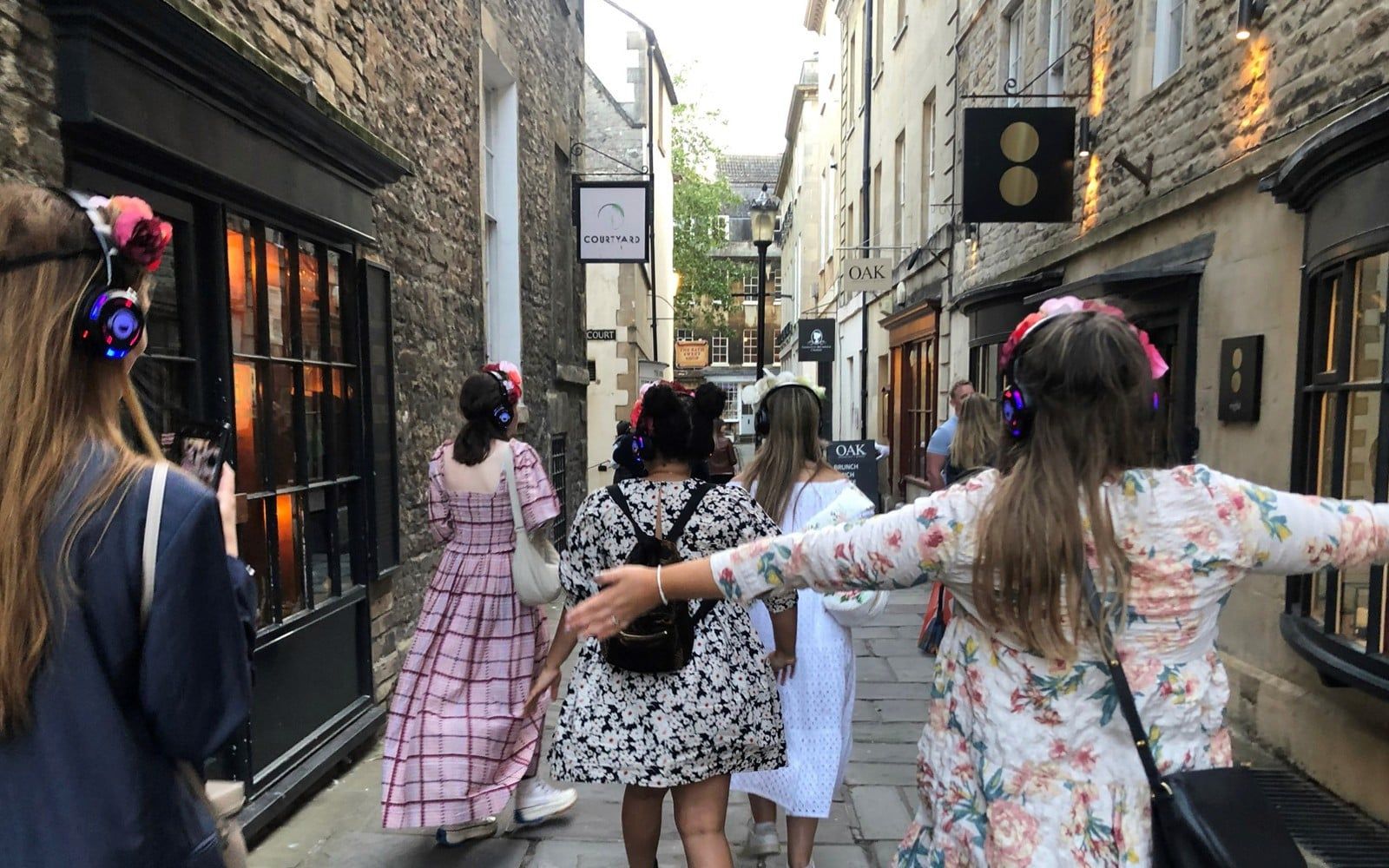 Tour group in period costumes with headphones walking through Bath's historic streets — Bridgerton: 1.5 Hour Guided Tour of Filming Locations in Bath with Music