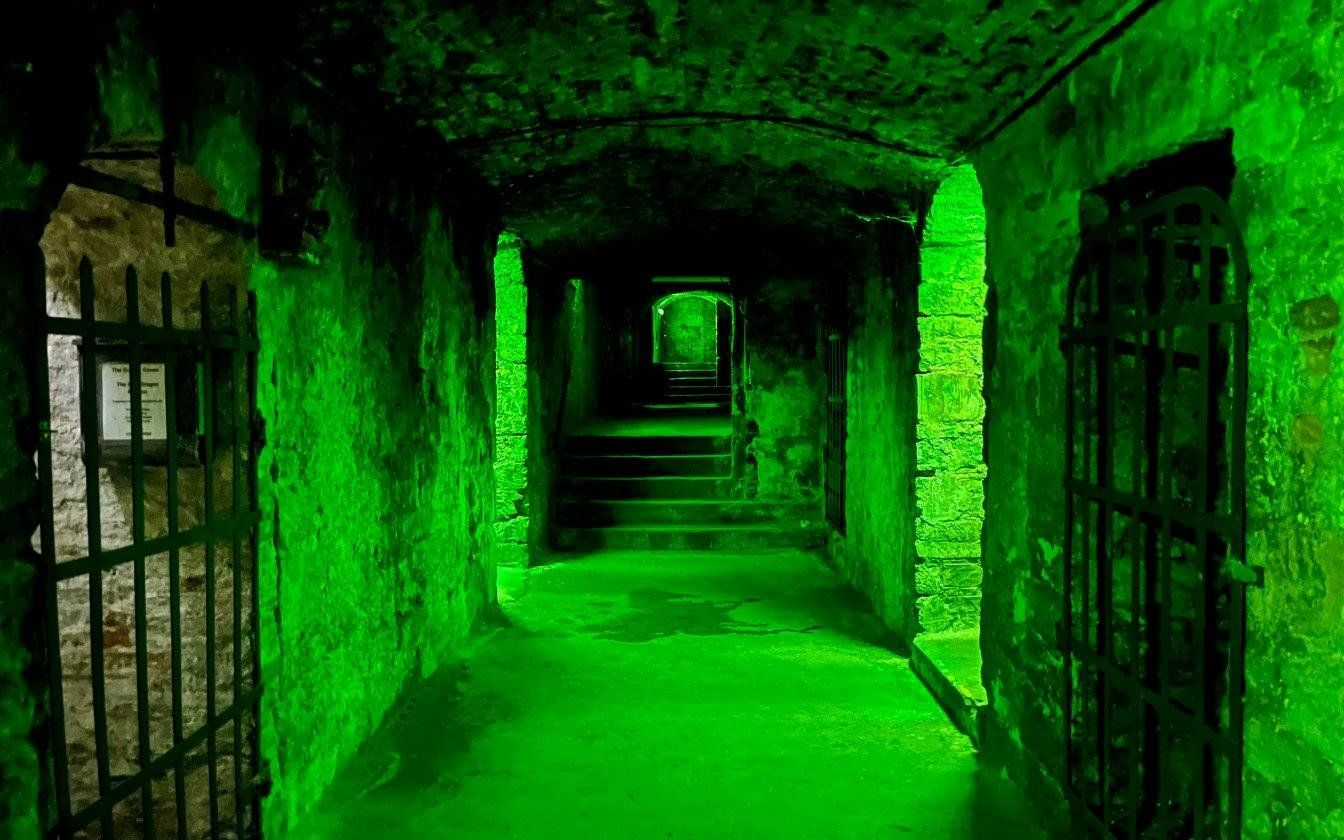 Underground passageway with green lighting on the Terror Tour in Edinburgh.