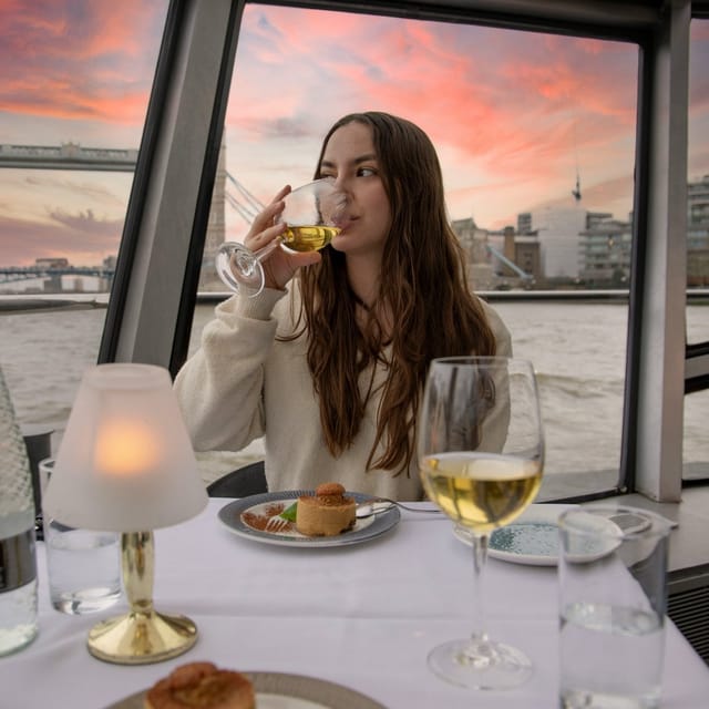 Thames dinner cruise boat passing Tower Bridge at night with London landmarks illuminated