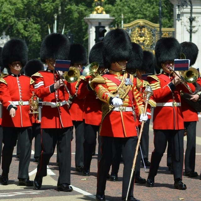 Guards in red tunics and bearskin hats marching to Buckingham Palace during the Changing of the Guard